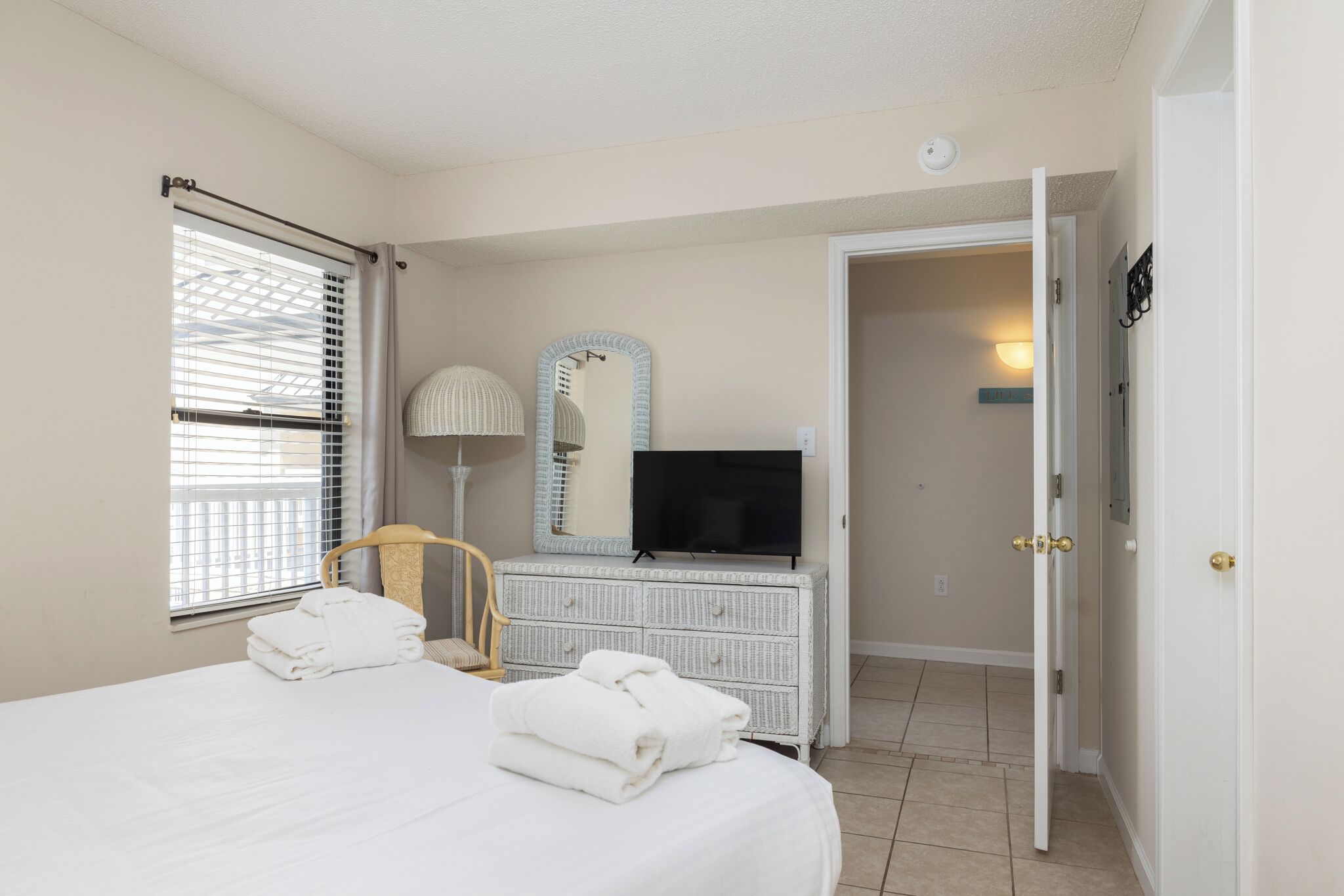 A hotel room with a bed, a television, a dresser, a chair, and a door leading to another room.