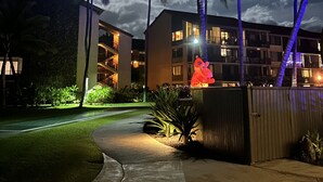 Un hotel con un vialetto ben illuminato, palme e un edificio su più piani dotato di balconi.