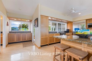 A modern kitchen with wooden cabinets, granite countertops, and a central island with stools.