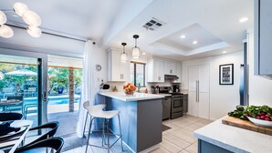 Cozinha moderna com ilha central, banquetas e vista para área de piscina externa.