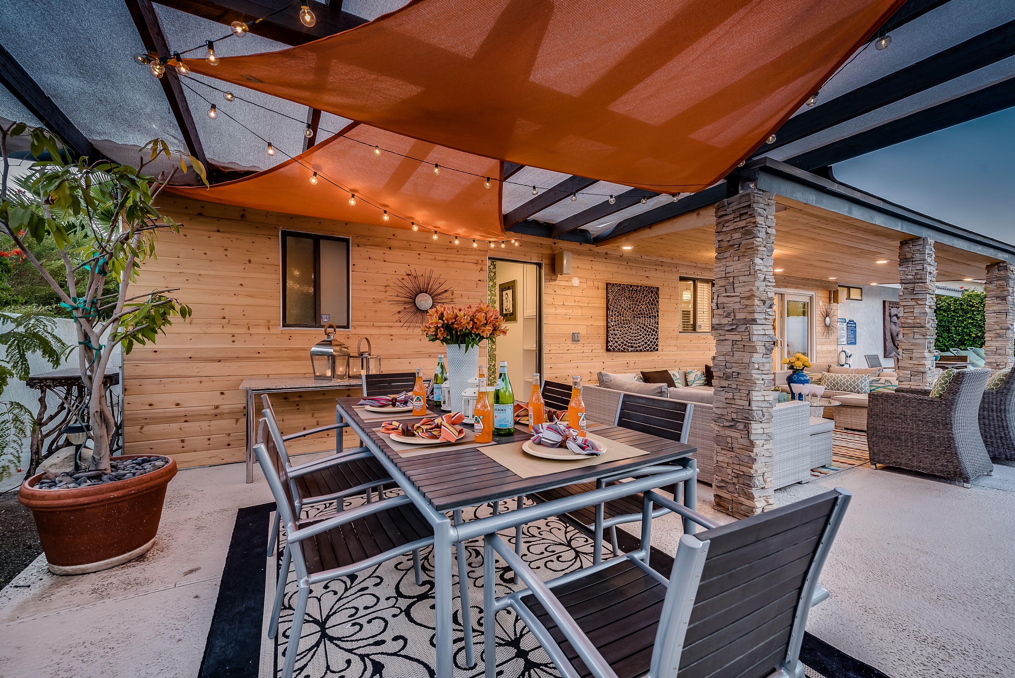 Eine Terrasse im Freien mit einem Esstisch, Stühlen und einem großen Sonnenschirm.