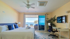A hotel room with a bed, a desk, a television, and a balcony with a view. - Le Papillon on the beach (Simpson Bay)