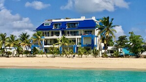 A beachfront hotel with multiple balconies, palm trees, and a clear view of the ocean. - Le Papillon on the beach (Simpson Bay)