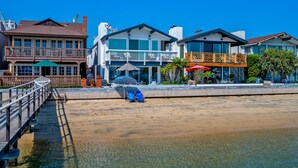 A beachfront property with a wooden deck, a covered seating area, and a view of the ocean.