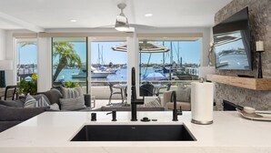 A modern kitchen with a large island, a built-in sink, and a view of the marina through large windows.