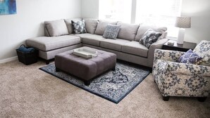 A living room with a sectional sofa, an ottoman, a patterned armchair, and a rug. - Beautiful Remodeled Home by Ski Resorts & Shopping (Sandy)