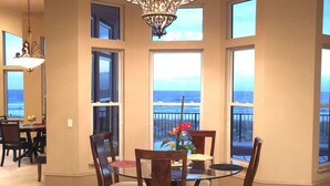 A dining area with a chandelier, large windows with ocean views, and a dining table with chairs. - Gulf Front, 3 Gulf Front Master Suites, Heated Balcony Pool  (Navarre)