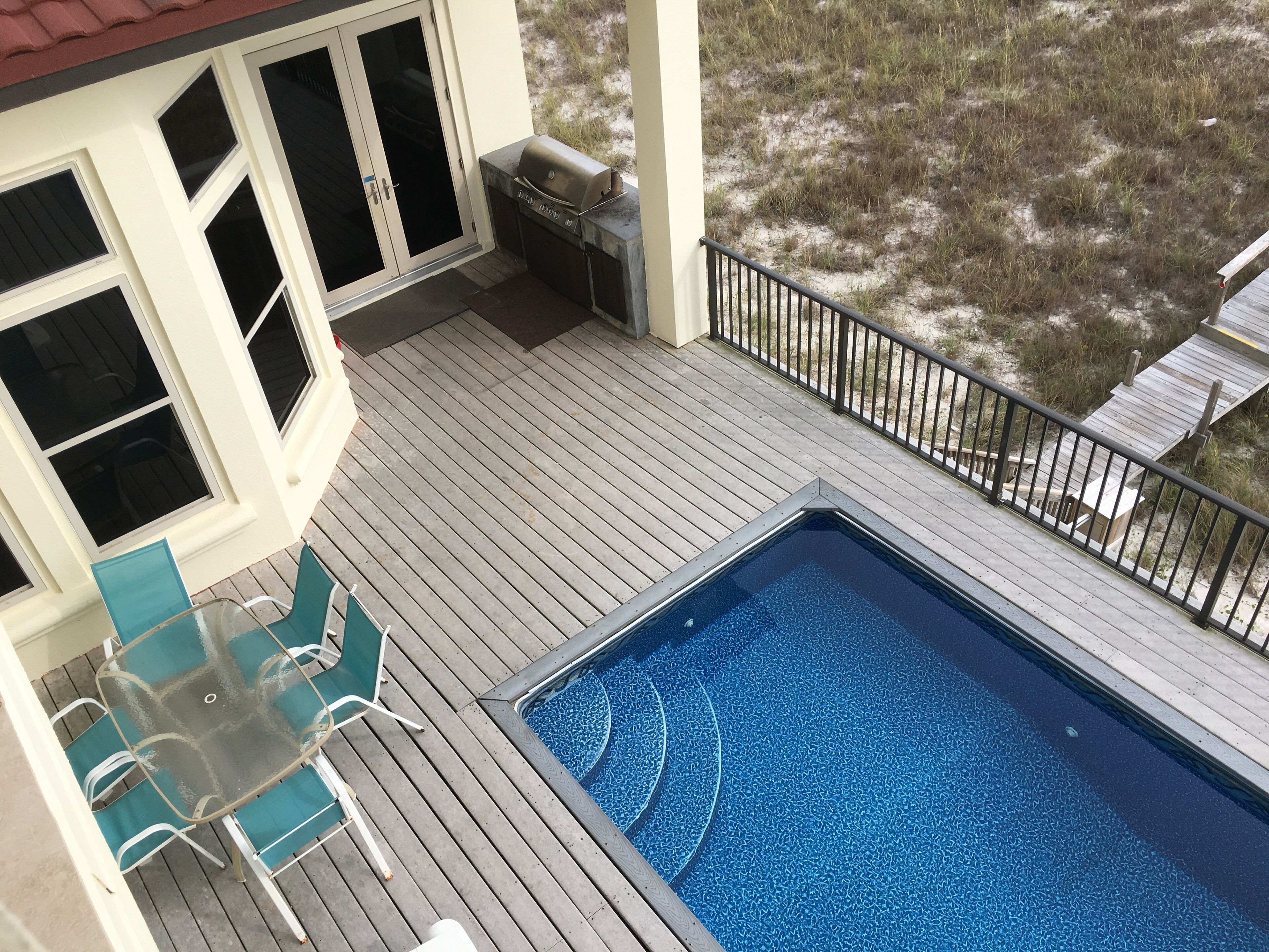 Une terrasse avec une piscine, un espace salon extérieur et un barbecue.