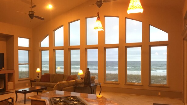 A spacious living room with large windows overlooking the ocean, a kitchen area with a marble countertop, and a ceiling fan. - Gulf Front, 3 Gulf Front Master Suites, Heated Balcony Pool  (Navarre)