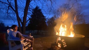 Eine Person sitzt am Abend bei einem Lagerfeuer.