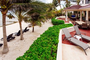 A beachside resort with lounge chairs, a dining area, and a covered patio.