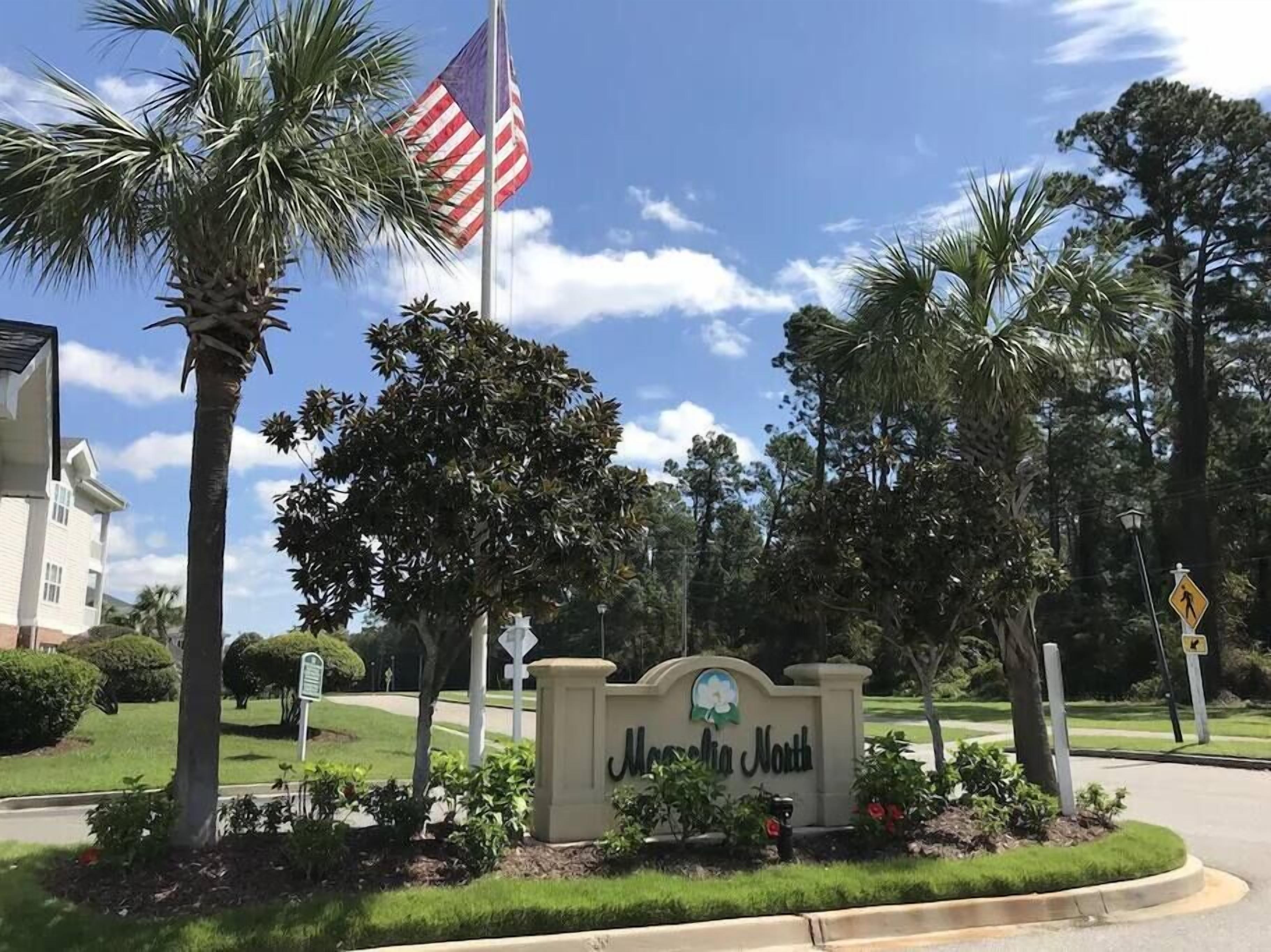 A sign for "Mansfield North" with a flag, palm trees, and a pedestrian crossing sign.