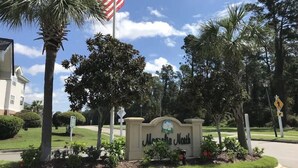 A sign for "Mansfield North" with a flag, palm trees, and a pedestrian crossing sign.
