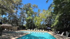 A rectangular pool with a 5 ft 6 in depth marker, surrounded by lounge chairs and a covered area, set against a backdrop of tall trees. - Private, Immaculate 4BR/4BA Home—community pool/tennis, minutes to beach/golf (Hilton Head Island)