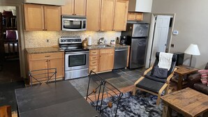 A modern kitchen with wooden cabinets, stainless steel appliances, and a dining area with a table and chairs. - Best Location Ski In/Out Condo @ Boyne Mountain- Walk To Village (Boyne Falls)