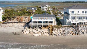 A beachfront property with a two-story house featuring a balcony and a staircase leading to a wooden deck. - Charleston Coast Vacations "Seascape Wonder" (Folly Beach)