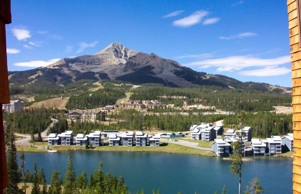 Un complejo turístico de montaña con varias construcciones, un lago y cielo despejado.