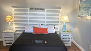 Un lit avec une couvre-lit noire, une tête de lit blanche et deux tables de chevet avec des lampes.