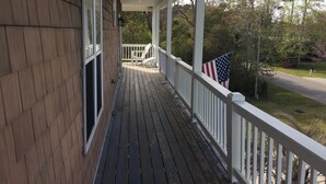 Une terrasse en bois avec une balustrade blanche et un drapeau américain.