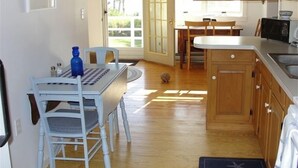 A kitchen with wooden cabinets, a dining table with chairs, and a large window. - Oceanfront Cottage in Milbridge ~ME~ (Milbridge)