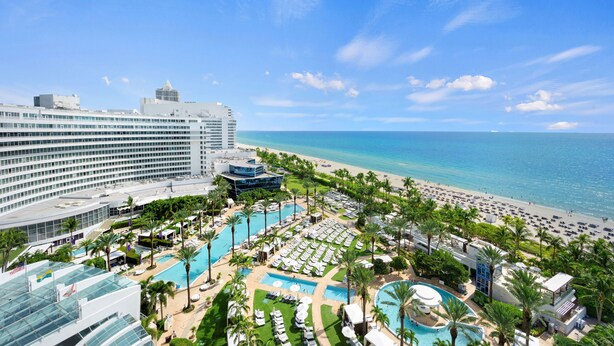 A resort with multiple swimming pools, a beach, and a large hotel building.