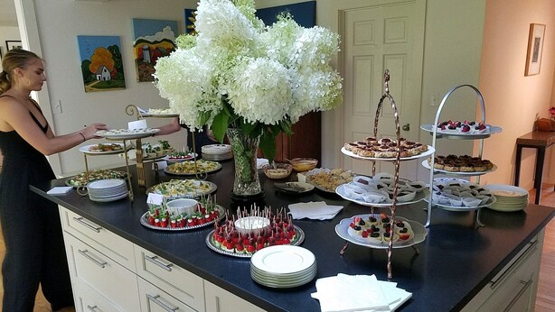 Ett bord med ett stort urval av desserter och en stor, vit blomsterdekoration.