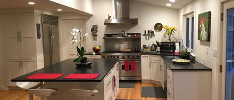 A modern kitchen with a central island, stainless steel appliances, and a skylight.