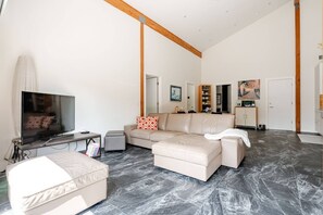 A living room with a TV, sofa, ottoman, and a dining area with chairs and a table. - Light & Bright 2BR - 2Baths, Patio, Fenced Garden, WIFI, Pet friendly, 30d+ ok (Clyde Hill)