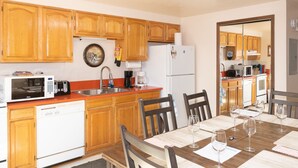 Una cucina compatta con mobili in legno, un forno a microonde, una macchina da caffè e una lavastoviglie.