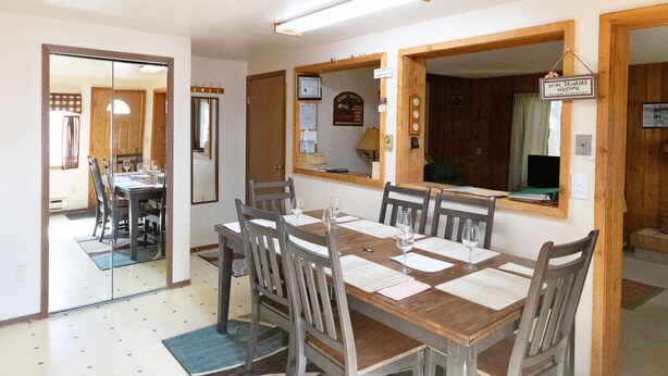Zona pranzo con tavolo e sedie in legno, uno specchio e un cartello di benvenuto per gli amanti del vino.
