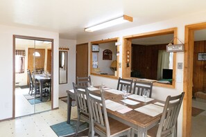A dining area with a wooden table and chairs, a mirror, and a sign welcoming wine drinkers. - QUIET 4 BDRM 2 BA FULLY EQUIPPED CONDO, 7 BLKS TO YELLOWSTONE PARK, HI-SPD WI-FI (West Yellowstone)