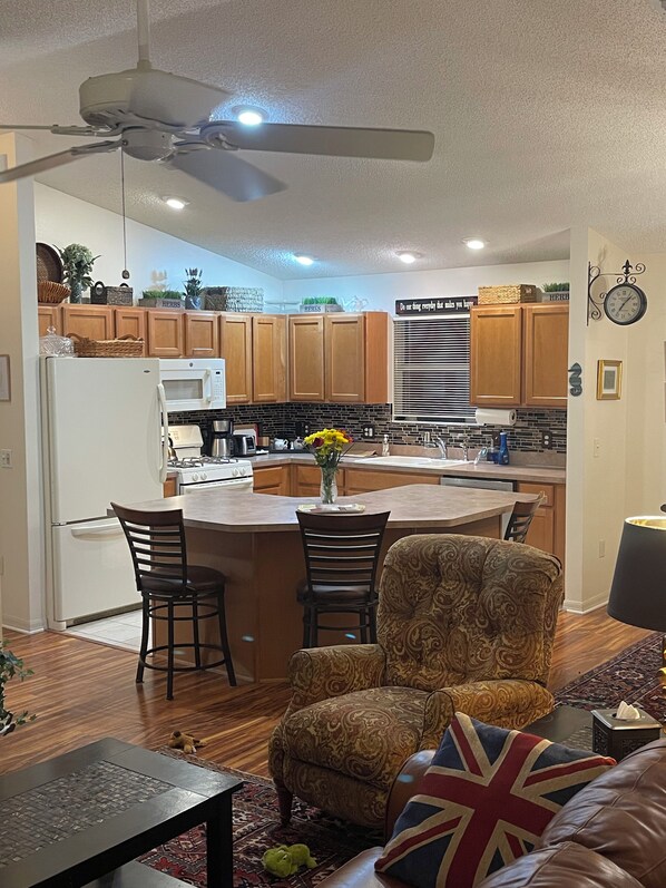 Una cocina moderna con armarios de madera, una isla central y un comedor con sofá estampado y una mesa.