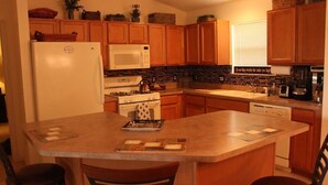 A kitchen with wooden cabinets, a refrigerator, a microwave, a stove, and a sink.