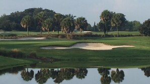 A golf course with sand bunkers, water hazards, and trees.