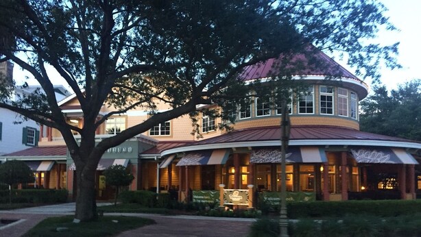 A hotel with a curved roof, a central courtyard, and a large tree in front.