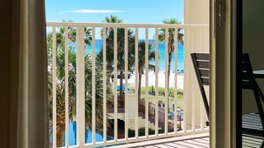 A balcony with a view of a pool and palm trees.