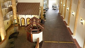 A hotel lobby with a central staircase, a small wooden structure, and a vehicle in the background.