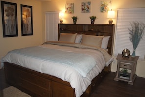 Relax in a serene bedroom with a large bed, nightstand, and framed artwork.