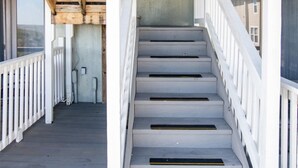 A wooden staircase with white railings leading to an upper deck area.