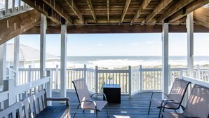 A wooden deck with white railings overlooking a beach.