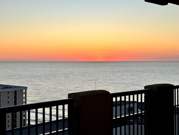 Un balcón con vistas al mar durante el atardecer.