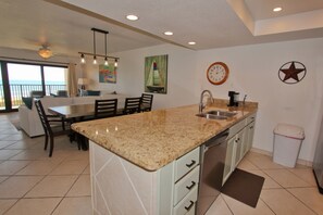 A kitchen with a granite countertop, stainless steel sink, and a coffee maker. - Shore to Please - Condo 402: A cozy oceanfront  2-bedroom retreat in South Padre Island. (South Padre Island)