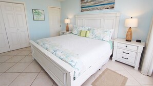 Une chambre à coucher avec un lit, deux tables de chevet, une commode, une porte et un tableau au mur.