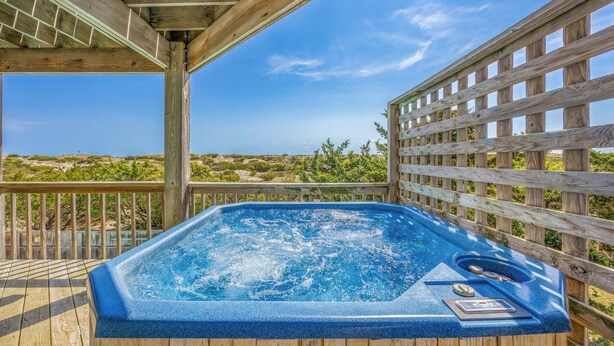 A hot tub on a wooden deck with a view of the landscape.