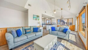 A spacious living area with two grey sofas, a white coffee table, and a kitchen in the background.