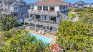 A multi-story residential building with a swimming pool, balconies, and a view of neighboring houses.