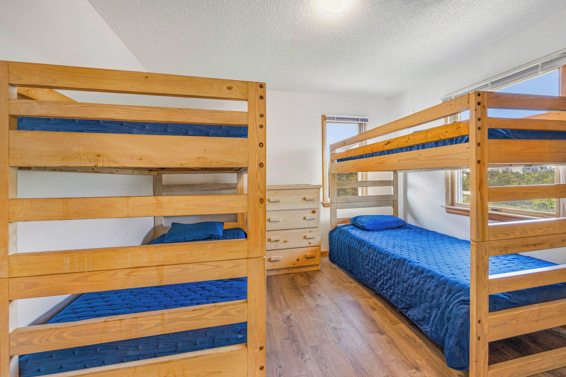 Habitación con literas de madera, un aparador y una ventana.