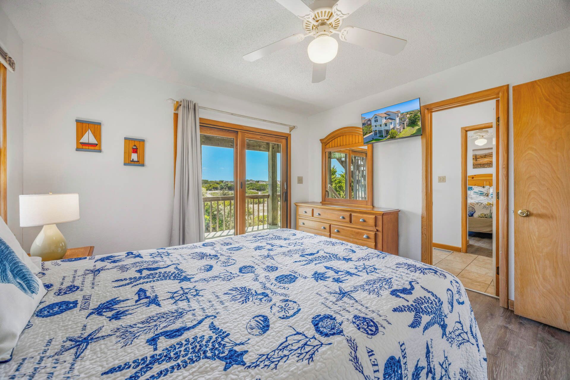 A bedroom with a bed, a dresser, a mirror, and a door leading to another room.