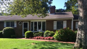 A two-story house with a front porch, a brick chimney, and a well-maintained lawn. - Relax and enjoy this private location in Hampton Bays (Hampton Bays)