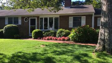 A two-story house with a front porch, a brick chimney, and a well-maintained lawn.
